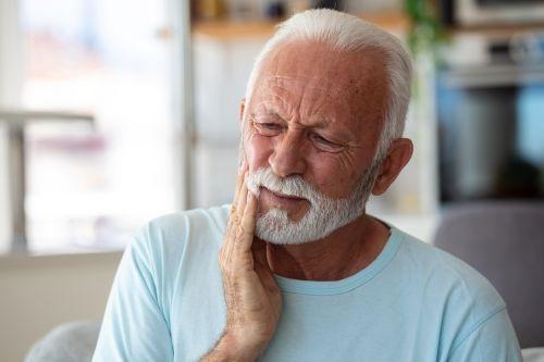 An elderly man holding his cheek in pain in Columbia, Md